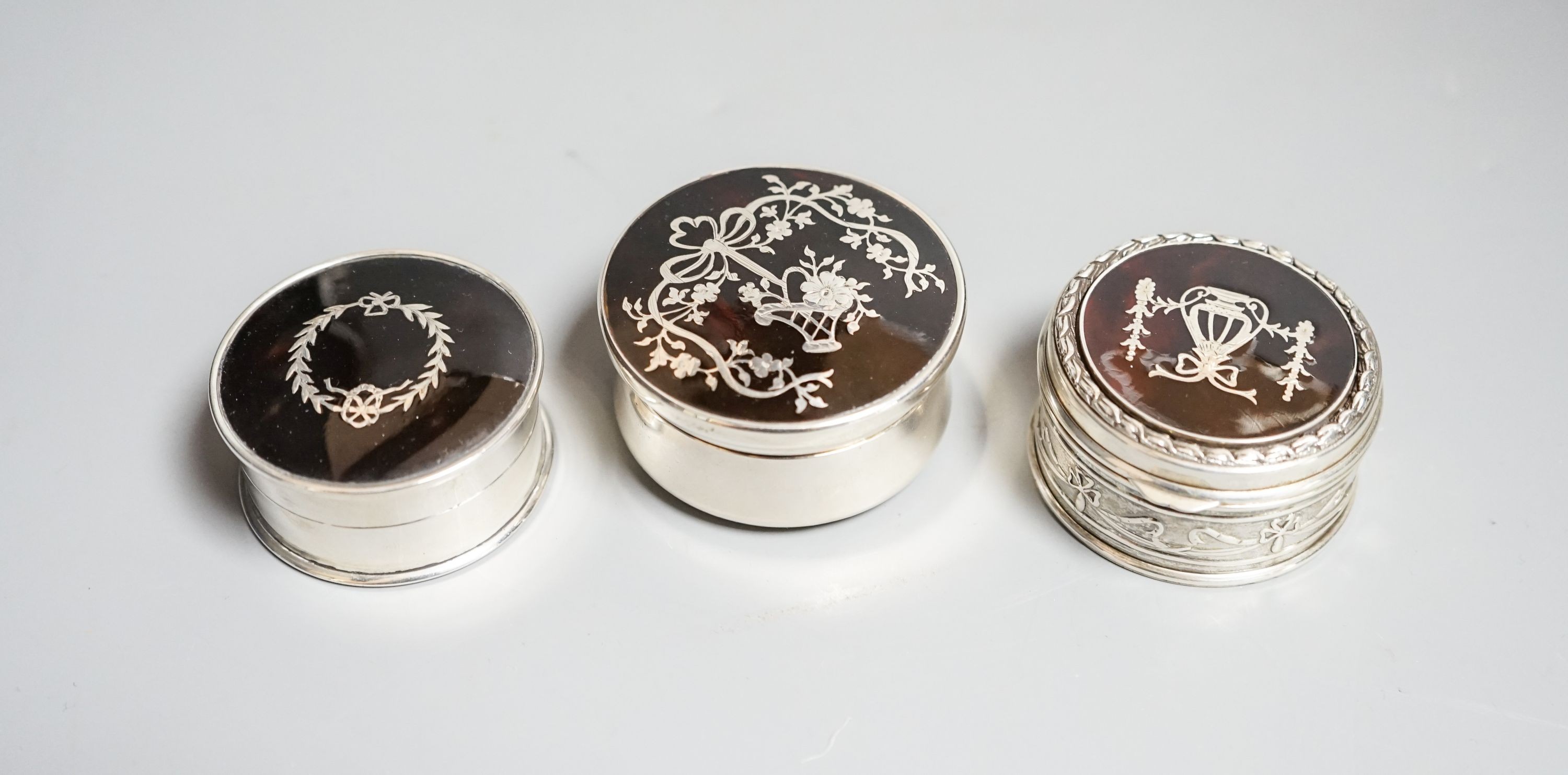 Three assorted early 20th century silver and tortoiseshell pique circular boxes and covers, two by Levi & Salaman, largest 58mm.